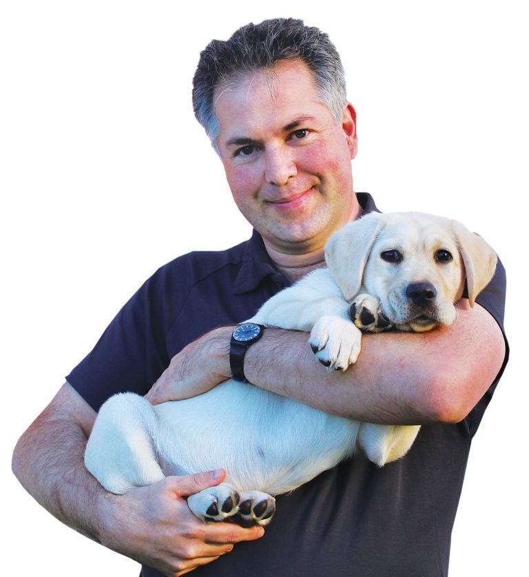 Image of a man holding a yellow Guide Dog puppy