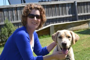 Image of a woman crouching beside a yellow Guide Dog