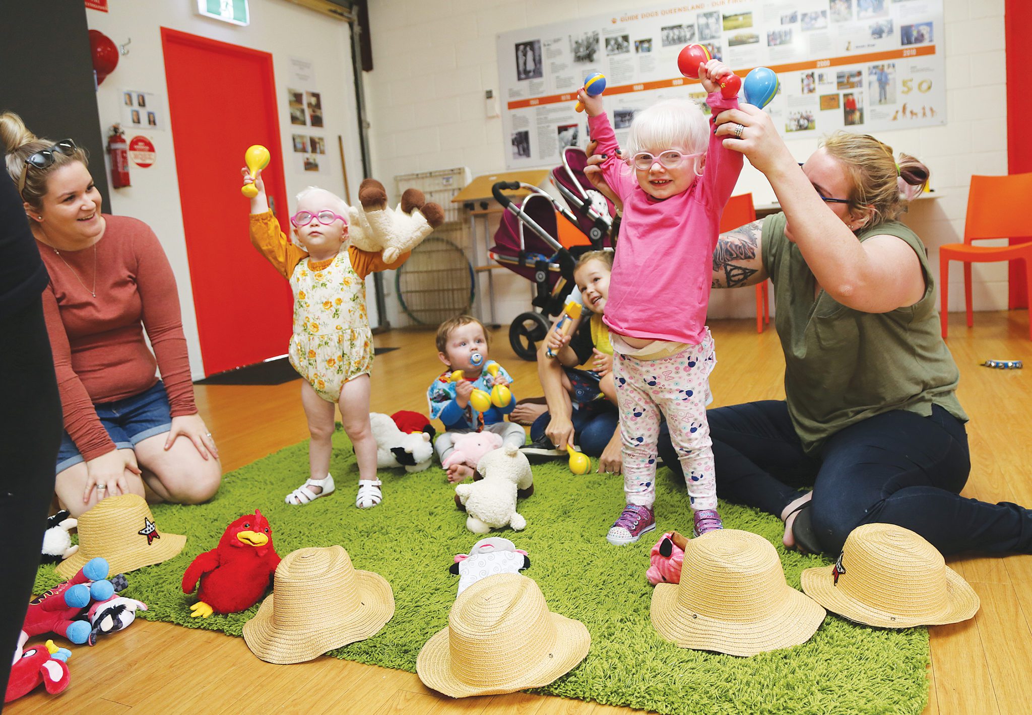Image of young kids and their mothers playing with colourful musical instruments