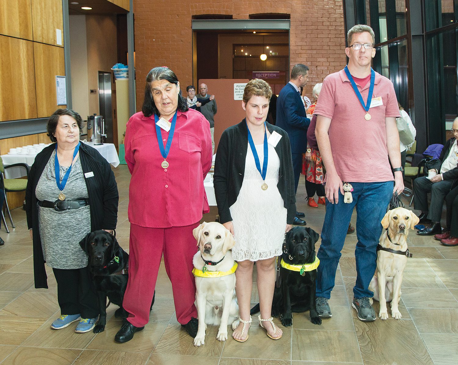 Image of four Guide Dog handlers wearing medals and posing proudly with their new Guide Dogs