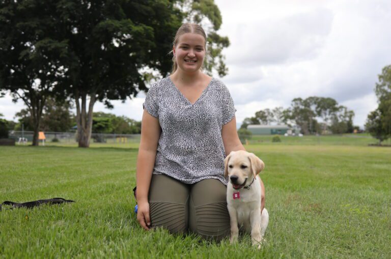 Chloe kneeling on the grass with pup 'Vanda'.