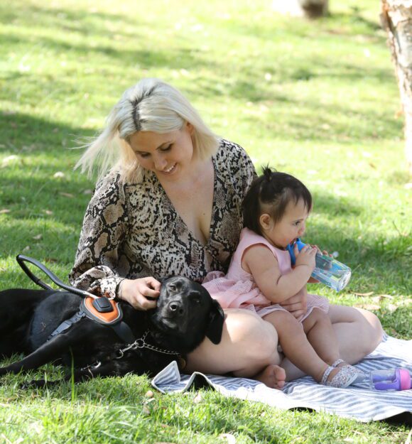 Ebony and Hollie wqith one Ebony's children, sitting on a picnic rug on the grass.