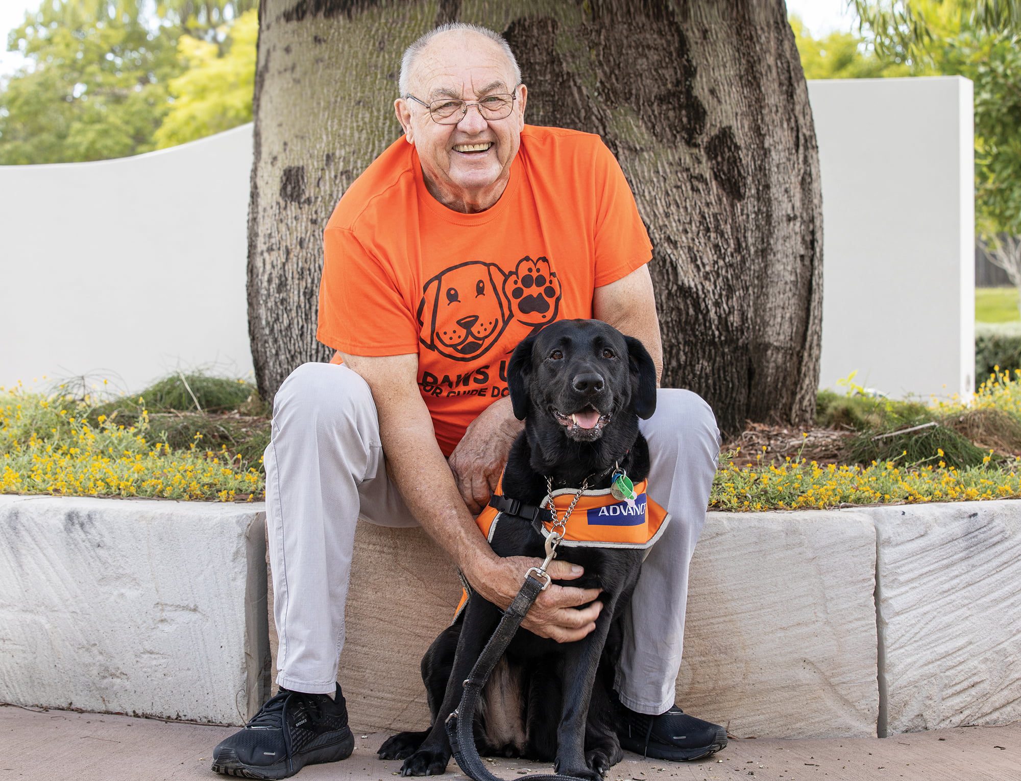 Image of Alan and his Guide Dog Ayla sitting in front of a tree looking at the camera.