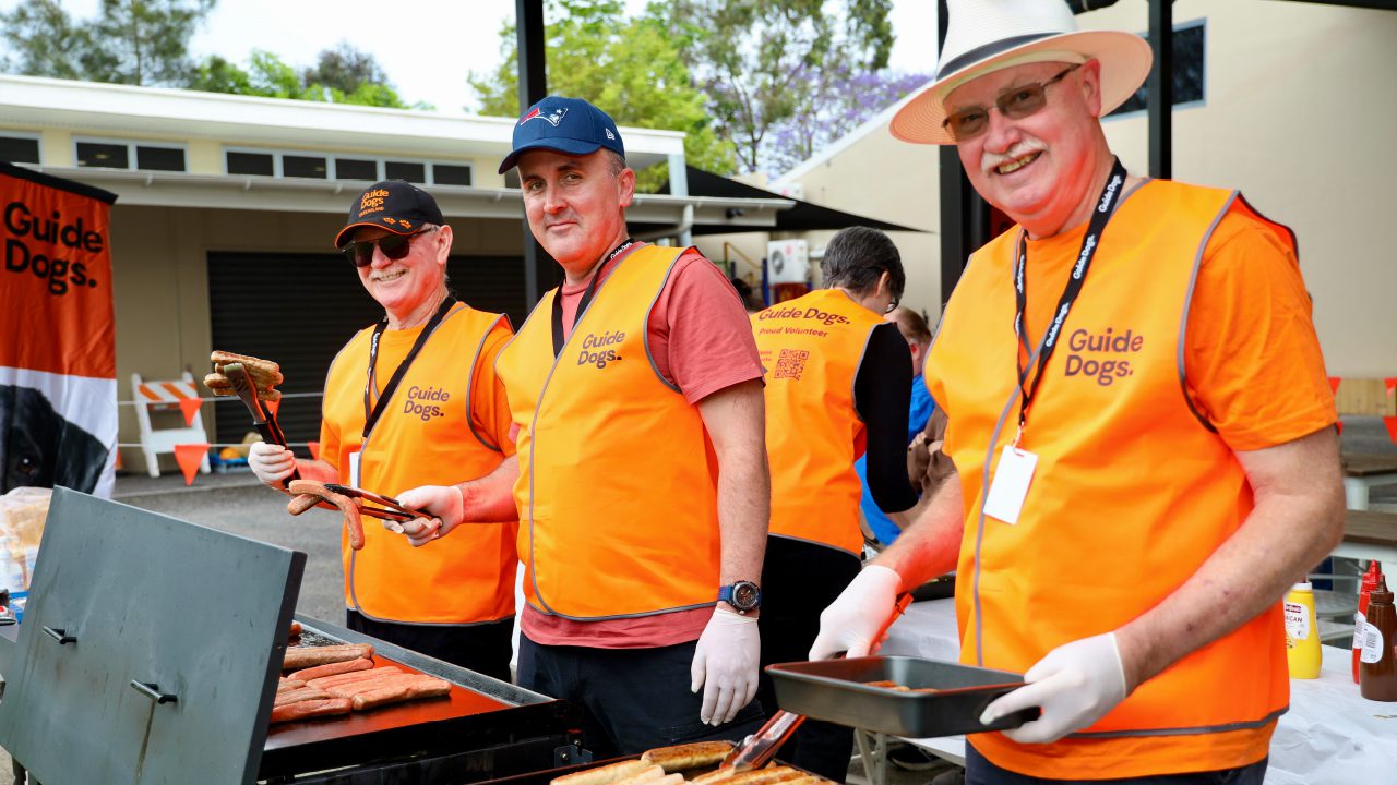 Image shows three volunteering standing in front of a barbeque.