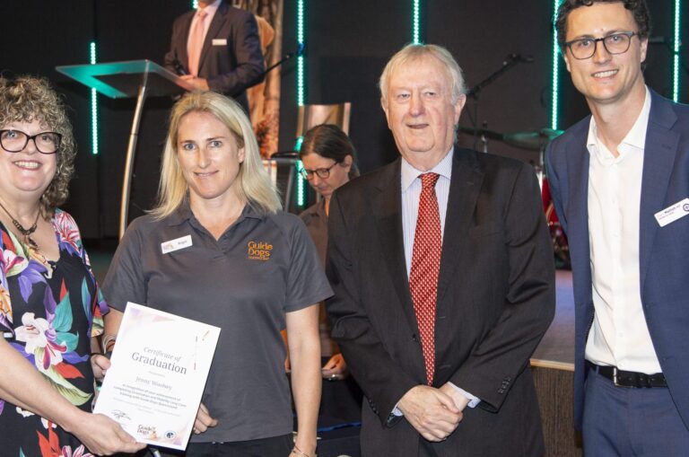 Jenny at the 2019 Guide Dogs Graduation ceremony standing beside a Guide Dogs instructor, president Richard Anderson and Member for Aspley Bart Mellish.