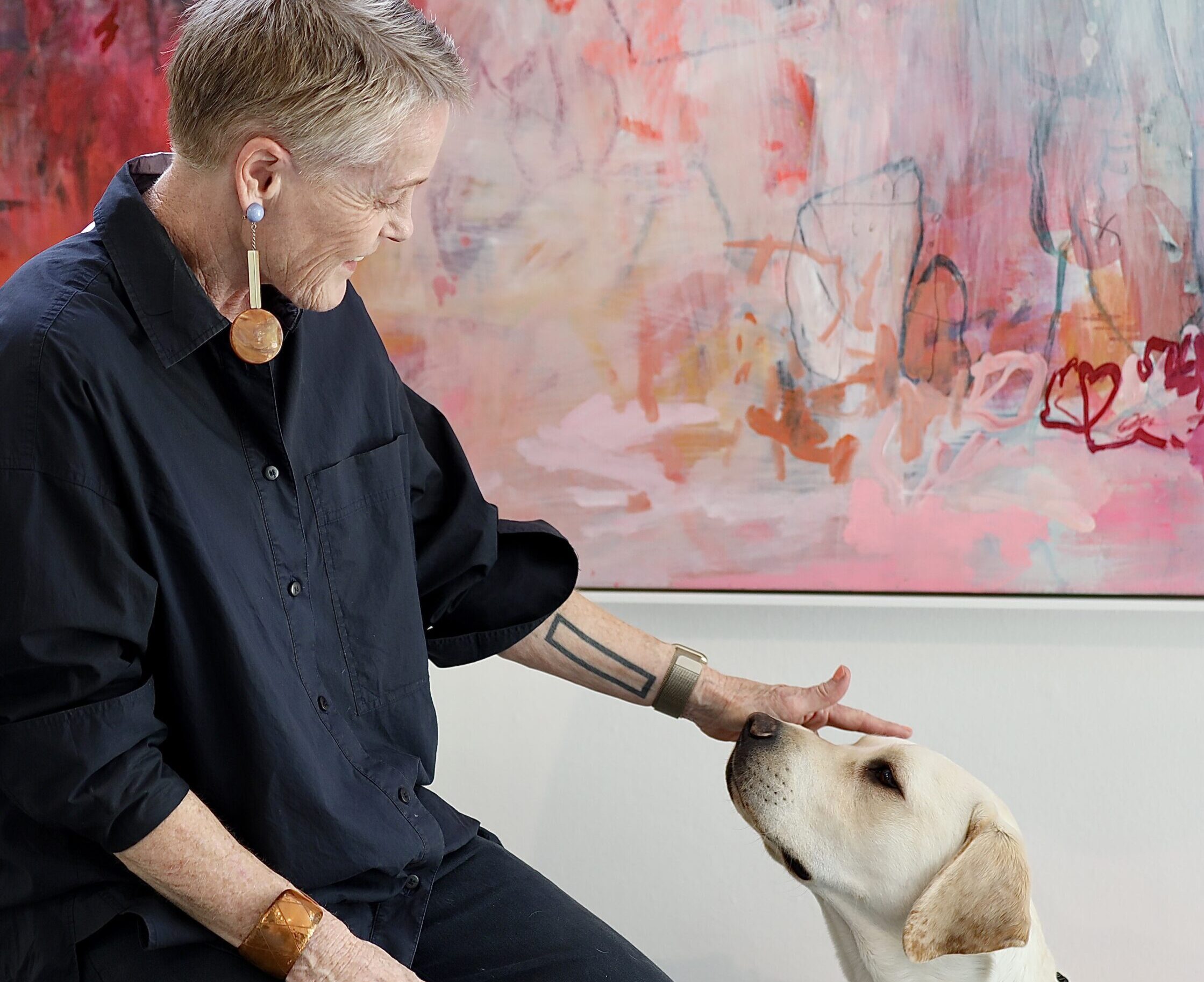 Image of Leesa next to some artwork with a Guide Dog in training next to her.