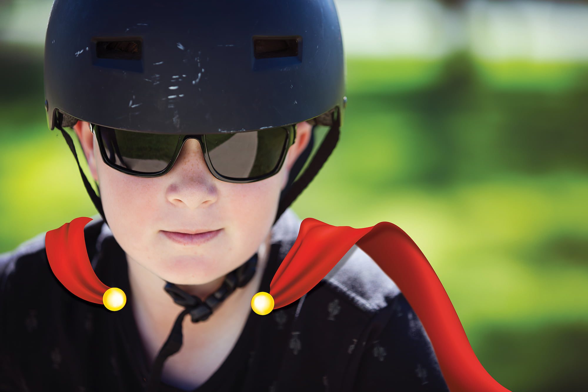 image of lindsay, a young boy with a cape and a helmet on, with sunglasses, looking at the camera