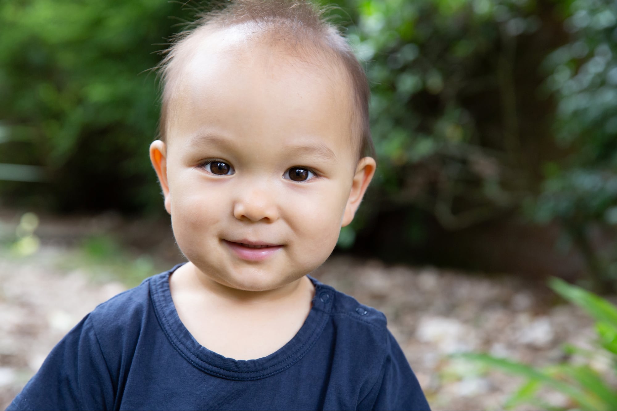 A young baby looking at the camera with a small smile on their face.