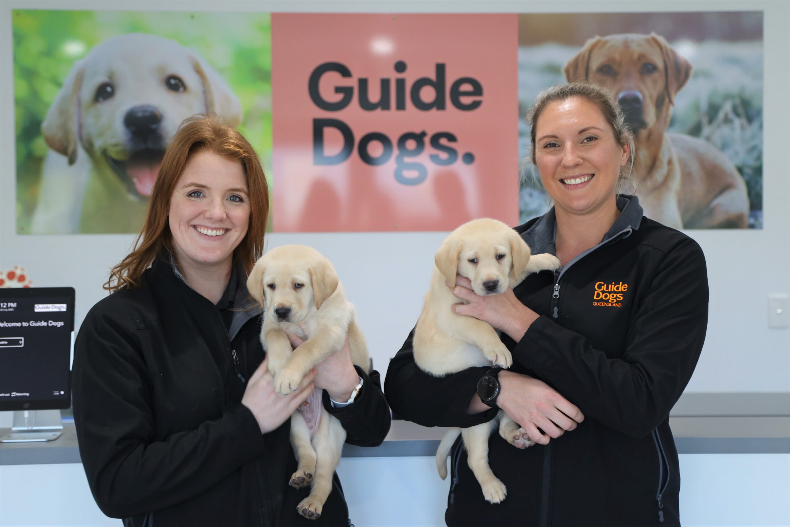 Image of our new vets, Amber and Lisa holding young yellow puppies