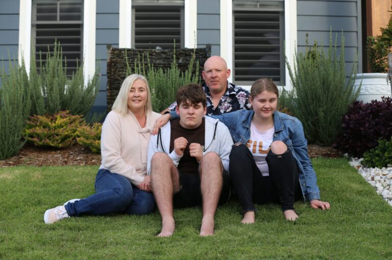 Nicole sitting on the grass with her husband and two kids.