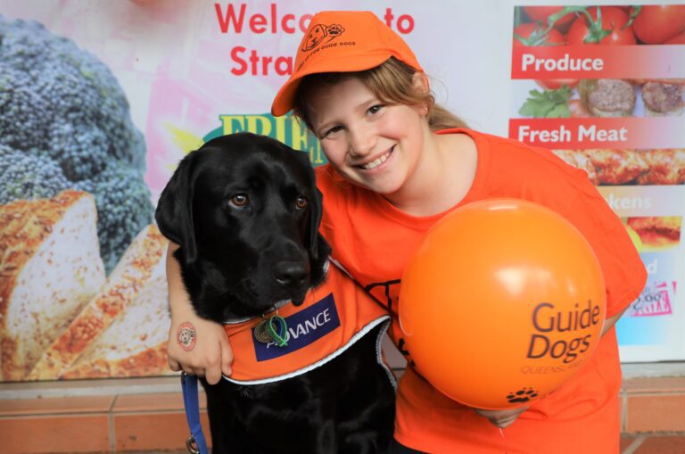 An image of a young girl hugging a yellow Guide Dog.