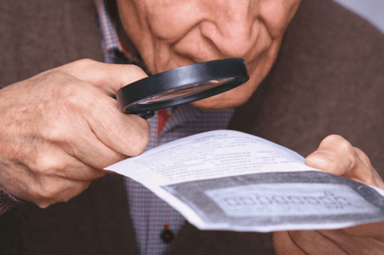 A man using a magnifying glass to read a document.