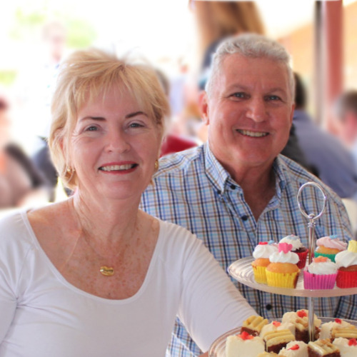Smiling couple enjoying afternoon tea at a community event.
