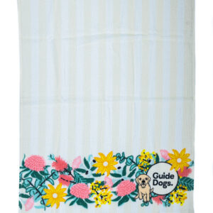 A tea towel with a floral banner pattern and a Guide Dogs logo at the bottom.